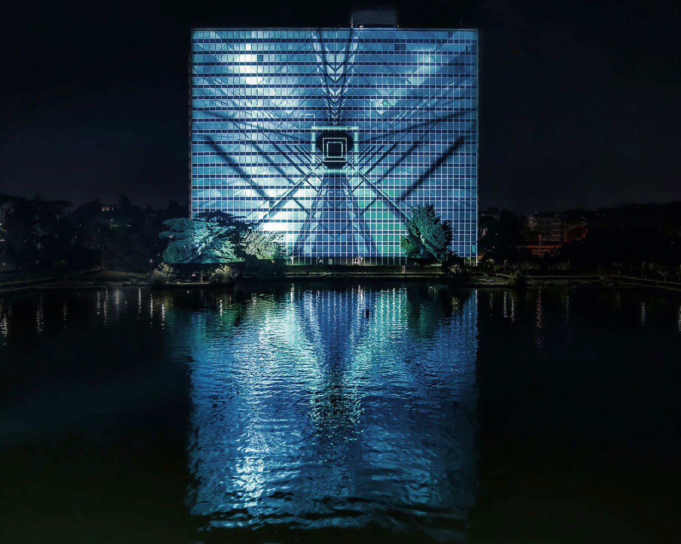 Glass-fronted building with a dazzling abstract blue design projected on it.