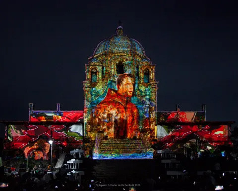 Domed building with a colorful image of a monk and stained glass imagery projected on it.